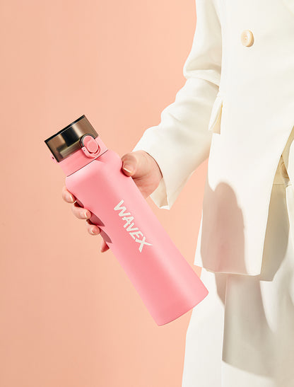 A woman in a white suit holds a stainless steel 550ml pink water bottle, showcasing a stylish and functional accessory.