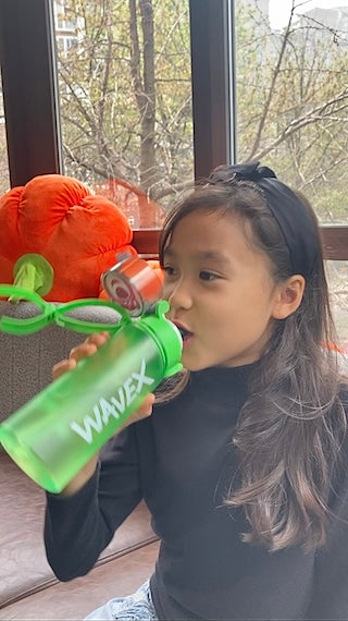 A young girl enjoying a refreshing drink from a 550ml green water bottle with a honey peach flavor