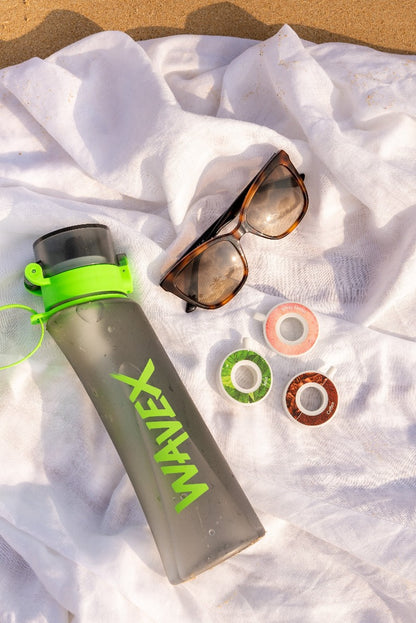 A pair of stylish sunglasses resting beside a 600ml green bottle, evoking a refreshing coffee experience